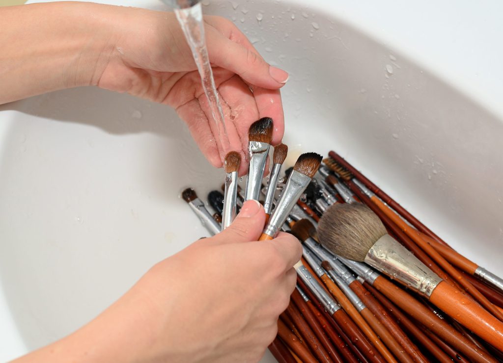 hands of make-up artist washed cosmetic brushes with clean water